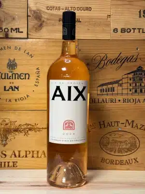 Elegante fles Aix Rosé met zachte zalmroze kleur, gepresenteerd in een zomerse setting – symbool van Provençaalse verfijning.