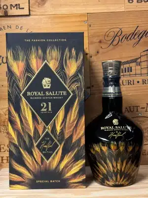 Limited edition Royal Salute 21 Year Old Harris Reed Gold Edition, in een goudkleurige keramische fles met elegante reliëfdetails en mode-geïnspireerde illustraties, ontworpen in samenwerking met ontwerper Harris Reed, gepresenteerd in een luxe doos met artistieke flair.