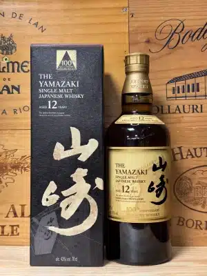 Fles Yamazaki 12 Year Old 100th Anniversary Edition, met speciaal zwart-wit label in Japanse kalligrafiestijl en gouden accenten, ter ere van het 100-jarig jubileum van de distilleerderij, gepresenteerd in een elegante zwarte doos met verfijnde details.