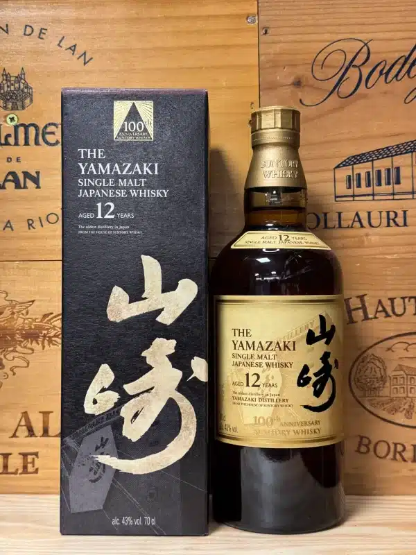 Fles Yamazaki 12 Year Old 100th Anniversary Edition, met speciaal zwart-wit label in Japanse kalligrafiestijl en gouden accenten, ter ere van het 100-jarig jubileum van de distilleerderij, gepresenteerd in een elegante zwarte doos met verfijnde details.
