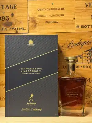 Exclusieve fles John Walker & Sons King George V blended Scotch whisky, met luxe vierkante decanterstijl fles, gouden details en koninklijk wapen op het label, gepresenteerd in een stijlvolle donkerblauwe geschenkdoos met fluwelen interieur.