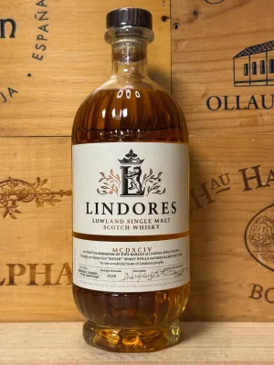 Fles Lindores Abbey Single Malt Scotch Whisky met gouden label en amberkleurige whisky, gefotografeerd voor de abdijruïnes.